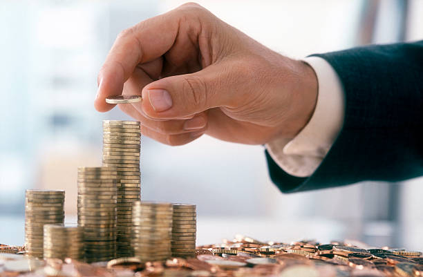 Hand of a mid adult man, wearing a siut, is stacking Euro coins. (2XL-File)